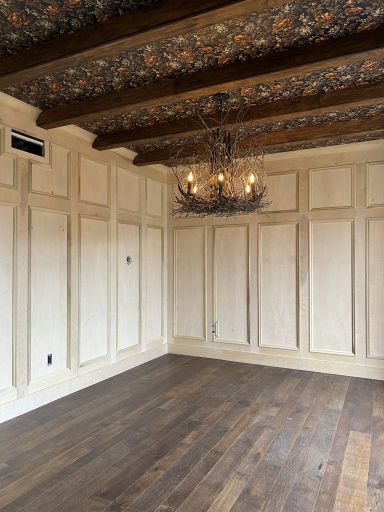 living room with wood beams and millwork and wallpaper on the ceiling