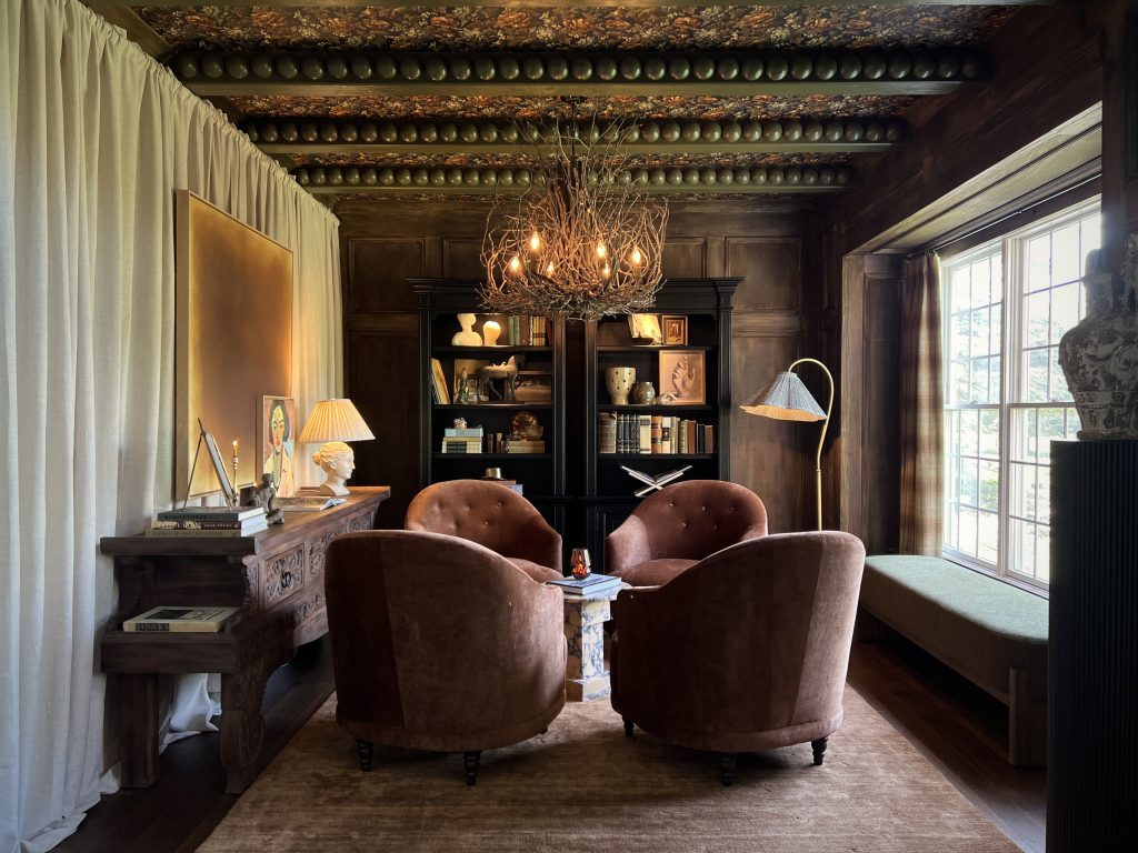 living room with wallpapered ceiling and painted green beams with bobbin trim and four rust chairs and a fabric wall