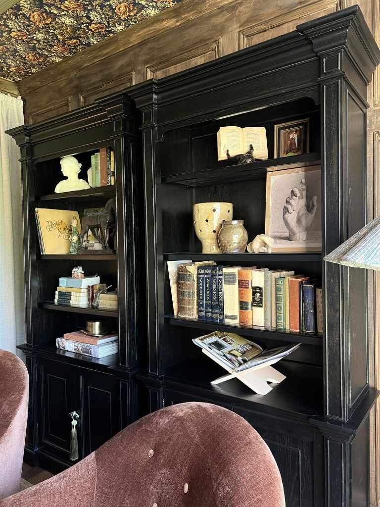 black hooker bookcases in living room with wood walls